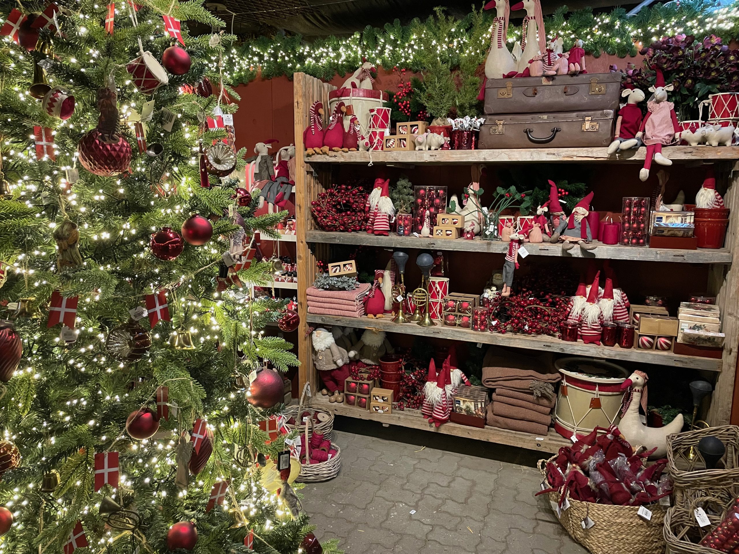 Julestuen hos Grønne Hjem Gentofte. Hylder fyldt med julepynt i røde nuancer samt et stort juletræ med rødt pynt og lys.